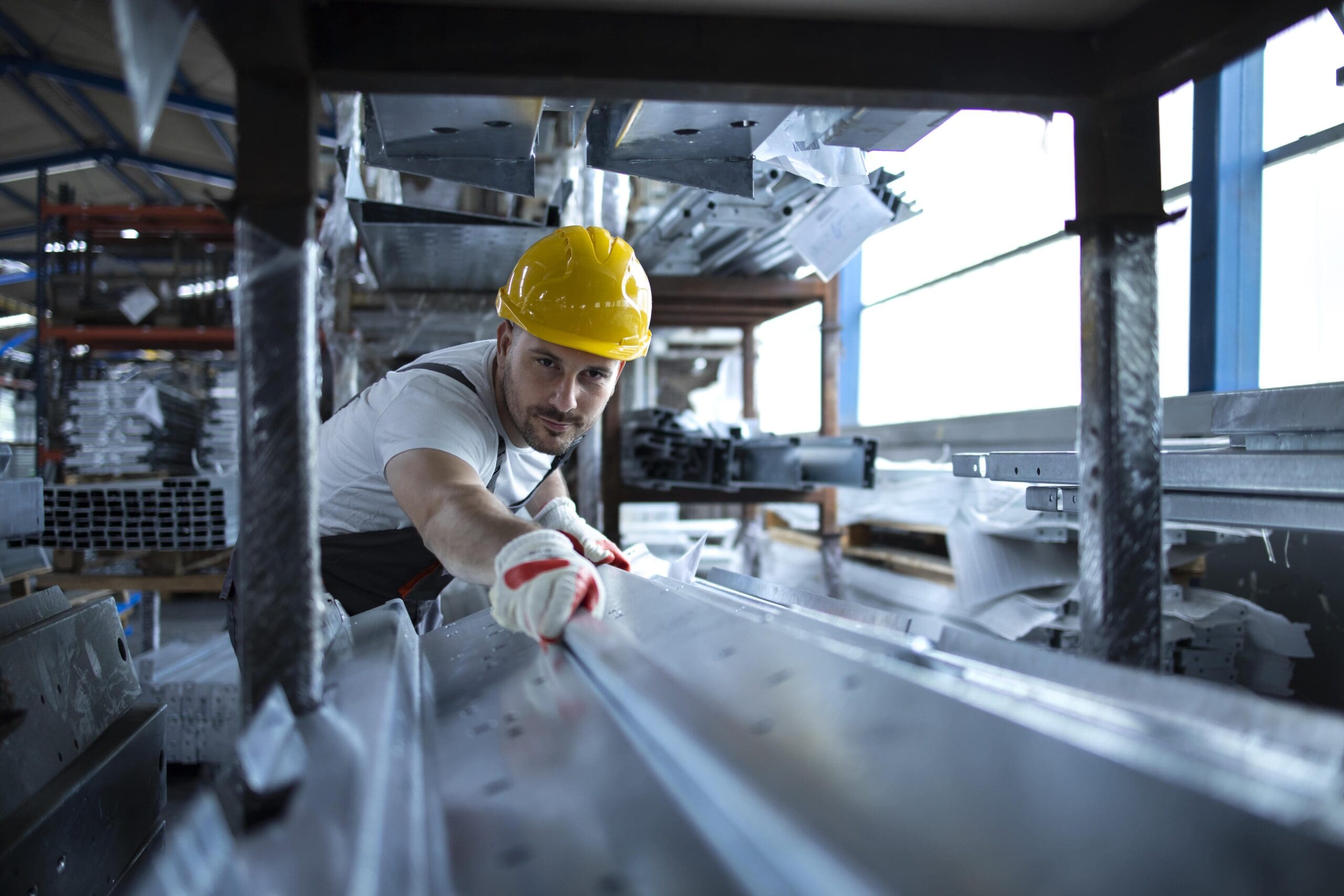 Factory worker at a warehouse handling metal material for a production line.